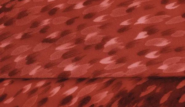 Kırmızı tekstil bulanıklığı ve organik formlara benzeyen karmaşık desenler. Bu yakın çekim yumuşak ışıkla vurgulanmış hassas kumaş kıvrımlarını yakalar ve zarif hissini arttırır..