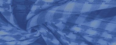 Mavinin tonlarında bulanık kumaş, kareli ve dokunmuş bir doku, yumuşak gölgeler ve kıvrımlar, tekstil bileşimine sanatsal ve karmaşık bir dokunuş katlıyor..