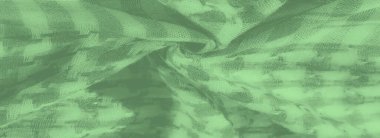 Yumuşak ekose desenli yeşil katlanmış kumaş bulanıklığı. Örgü dokusunu vurguluyor. Işık kumaşın detaylarını yakalar, derinliğini ve boyutunu yeşil tonlarda vurgular..