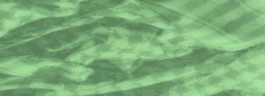 Katmanlı kareli desenli Bulanık Yeşil kumaş dokunmuş yapısını vurguluyor ve kumaşların üzerindeki ışık ve gölge karışımından derinlik ekliyor.