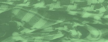 Katmanlı kareli desenli Bulanık Yeşil kumaş dokunmuş yapısını vurguluyor ve kumaşların üzerindeki ışık ve gölge karışımından derinlik ekliyor.