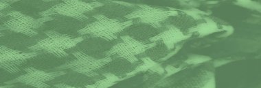 Görüntü. Katmanlı damalı yeşil kumaş, dokuma yapısını vurguluyor ve kumaşların üzerindeki ışık ve gölge karışımından derinlik ekliyor..