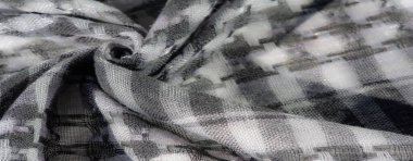 Görüntü. Katmanlı damalı yeşil kumaş, dokuma yapısını vurguluyor ve kumaşların üzerindeki ışık ve gölge karışımından derinlik ekliyor..