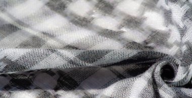 Görüntü. Katmanlı damalı yeşil kumaş, dokuma yapısını vurguluyor ve kumaşların üzerindeki ışık ve gölge karışımından derinlik ekliyor..