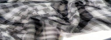 Detaylı ağ ve ızgara benzeri desenli bulanık gri pullu tekstil, kumaşın karmaşık dokuma yapısında koyu ve aydınlık zıtlıkları vurgulayan kıvrımlar oluşturuyor..