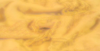 Yumuşak kıvrımları ve karmaşık dokuları olan ılık sarı kumaş bulanıklığı. Işıklandırma, kumaşın dokunmuş hassas detaylarına sıcak bir parıltı ekler. Yumuşak ve davetkar hissettirir..