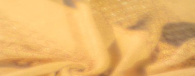 Karmaşık, örtüşen kıvrımlı bulanık sarı kumaş yumuşak ışıklandırma ve gölgelendirme efektleriyle vurgulanmış davetkar bir sıcaklık ve doku yüzeyi yaratır..