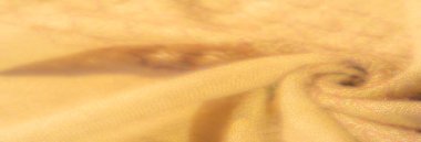 Yumuşak kıvrımlı sarı kumaşın bulanık görüntüsü, karmaşık dokunmuş detaylar, sıcaklığı yayıyor ve nazikçe aydınlatma ve gölgelendirme ile gelişen davetkar doku..