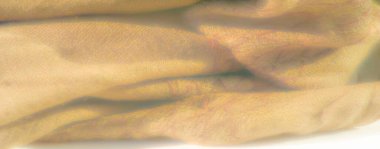 Yumuşak ve samimi bir görünüm oluşturan kıvrımlı, kıvrımlı sarı kumaştan oluşan bulanık bir görüntü. İnce kıvrımlar ve sıcaklık huzurlu bir görsel izlenim yaratıyor.