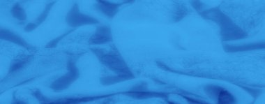 Dalgalanan kıvrımları ve yumuşak, pürüzsüz bir yüzeyi olan canlı mavi kumaş bulanıklığı, sakin ve dingin bir dokuyla tekstil sanatının zarafetini yakalıyor..