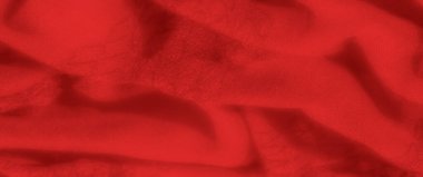 Yumuşak kıvrımlı, yumuşak kırmızı kumaşın bulanık görüntüsü lüks ve sıcak bir görünüm yaratıyor. Gölgeler yüzey boyunca oynarlar ve tekstil dokusuna zarif bir dokunuş eklerler.