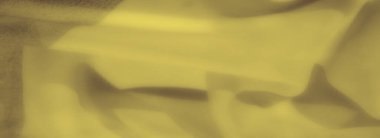 Sarı kumaştan bulanık. Nazik kıvrımlar ve yumuşak gölgeler. Huzurlu ve sıcak bir görsel doku sağlıyor..