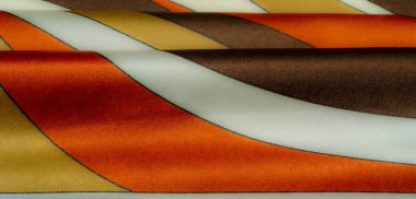 Parlak sarı, turuncu ve kahverengi çizgili kumaşlar, yumuşak kıvrımlı, lüks bir doku yaratıyor. Kalın renkler ve karmaşık desenler sıcaklık ve zarafet ekler..