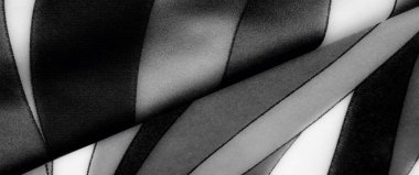 Gri tonlu kumaşın karmaşık kıvrımları büyüleyici bir ışık ve karanlık dansı sahnenin derinliğini ve dokusunu ekliyor. Kumaşlar zarif bir sükunet hissi uyandırıyor.