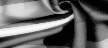 Bulanık, tek renkli kumaş koyu ve açık gri karışımlı, kıvrımlı desenler gösterir. Düz doku tasarımın hareketine zarafet ve derinlik ekler.