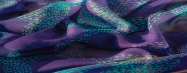 Görüntü, turkuaz renklerle güzel detaylı mor bir kumaş. Doku ve zarafeti ortaya çıkarmak için sanatsal olarak katlanmış. Renklerin ahenkli karışımı kumaşın gelişmişliğini arttırır.