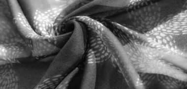 Görüntü. Gri tonlu kumaşın yakın plan görüntüsü. Hassas, yaprak benzeri bir desen. Yumuşak kıvrımlar gölgeler yaratır, dokuyu ortaya çıkarır ve yumuşak, akışkan görünümü güçlendirir..