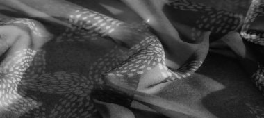 Görüntü. Ayrıntılı gri pullu kumaş yaprak benzeri şekiller ve doğal bir örtü. Yumuşak kıvrımlar ve hassas doku ışık ve gölge etkileşimiyle vurgulanır..