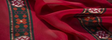 Görkemli yeşil ve turuncu geometrik kenarlı bulanık tekstil. Karmaşık çiçek desenleri ve parıltılı detaylarla kaplı..