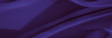 Görüntü. Pürüzsüz kıvrımları ve dalgalı kıvrımları olan koyu mor bir kumaş. İpeksi doku ve gölgeler zarif ve rüya gibi bir görünüm yaratır..