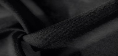 Görüntü, siyah kumaşın zengin dokusunu ve zarif kıvrımlarını sergiliyor. Yumuşak, pürüzsüz yüzeyini hassas ışık ve modern estetik için gölge geçişleriyle vurguluyor.