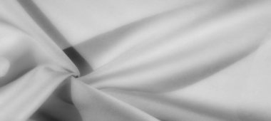 Ortasında dairesel bir bükülme olan gri tonda yumuşak kumaş. Yumuşak gölgeler düz dokuyu ve soyut tasarımı vurgular.