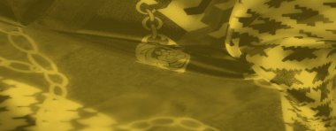 Karmaşık houndstooth ve zincir tasarımları pürüzsüz sarı kumaş üzerinde, parlak bir kapanış sunuyor ve modern zarafet canlı ayrıntılı olarak.