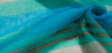 Canlı bir turkuaz kumaşın bulanık, narin kıvrımları ve parlak bir parıltısı var. Işığı güzel yansıtan, zarif dekorlar için mükemmel bir dokuya sahip..