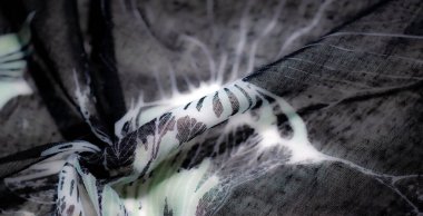 Katmanlı, şeffaf bir dokuda siyah ve beyaz karşıtlıkları içeren bulanık kumaş sanatı, materyalin bileşimine derinlik ve zarafet katıyor..