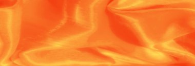 Canlı turuncu saten kumaş pürüzsüz, parlak bir dokuya sahip kıvrımlar sergiliyor. Parlak röfleler bir sıcaklık ve zarafet hissi yaratır..