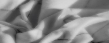 Gri tonlu kumaşın karmaşık çizgileri yumuşak kıvrımlarla buluşup büyüleyici bir tek renkli kompozisyonda uyumlu bir ışık ve doku dengesi yaratıyor..