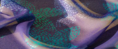 Canlı deniz mavisi aksanlı, desenli mor bir kumaşın bulanık görüntüsü. Karmaşık tasarım ve yumuşak örtü bir hareket ve zarafet hissi yaratır..