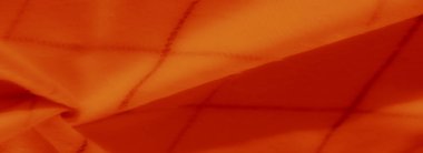 Bulanık turuncu kumaş katmanları ve ince ızgara desenleri dinamik bir tekstil etkisi için sıcak tonları ve pürüzsüz katları karıştırarak derinlik ve yumuşaklık hissi yaratır..