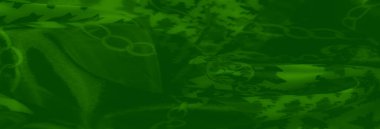 Siyah ve birbirine dokunmuş zincir benzeri desenlerle kalın houndstooth tasarımları olan yeşil kumaş bulanıklığı, tekstil dokusunun akış dokusuna derinlik ve boyut ekler..