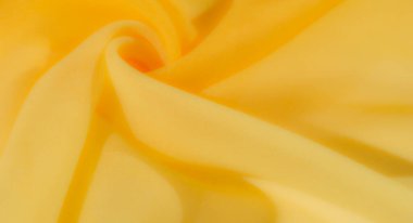 Bulanık, yumuşak, akışkan sarı kumaş kıvrımları hafif bir girdap etkisi yaratarak sıcaklık ve parlaklığı yakalıyor. Kumaşın narin dokusu pürüzsüz, neredeyse kadifemsi bir görünümü ön plana çıkarıyor.