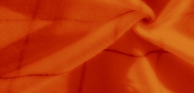 Kesişen koyu çizgiler ve yumuşak kıvrımlarla dokulu ve buruşuk desenli turuncu kumaş yakın plan. Canlı renk onun görsel çekiciliğini arttırır..