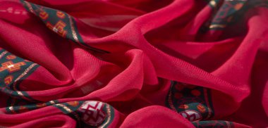 Kalın kırmızı, turuncu ve yeşil renklerde canlı çiçek ve geometrik tasarımların karmaşık etkileşimini bulanıklaştırarak gelişmiş ve ışıltılı bir tekstil yaratıyor..