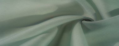 Nane yeşili bir bulanık kumaş, yarı katlı, yumuşak kıvrımlı. Işık ve gölge oyunu onun narin ve sakin çekiciliğini vurgular..