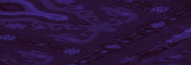 Çiçek ve geometrik desenler sergilenen zengin mor kumaşın bulanıklığı, sanatsal ve tekstil esinlenimlerine uygun bir zarafet ve karmaşık tasarım hissi yaratıyor..