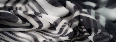 Kıvrımlı dalga desenleri olan katmanlı siyah beyaz kumaş. Sanatsal kıvrımlar ve asgari doku ona dinamik ve zarif bir görsel stil kazandırıyor..