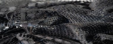 Siyah dantelli kumaşın bulanık soyut fotoğrafı. Karmaşık dokuma desenleri ve ışık yansımaları. Doku ve gölgenin dinamik etkileşimini yaratıyor..