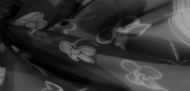 Bulanık görüntü, hafif kumaşta tek renkli çiçek desenleri gösteriyor. Yumuşak dokular ve akan kıvrımlar zarafeti ve sanatsal yaratıcılığı çağrıştırıyor..