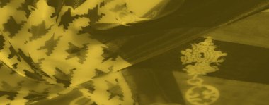 Bulanık sarı kumaş, kalın houndstooth izleri ve birbirine dolanan zincirler, dinamik ve canlı bir görsel kompozisyon sunuyor..