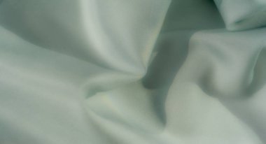 Yumuşak ışıklandırma ve narin gölgelerle zarifçe vurgulanmış nane yeşili kumaşların bulanıklığı rahatlatıcı ve minimal bir görsel cazibe yaratıyor.