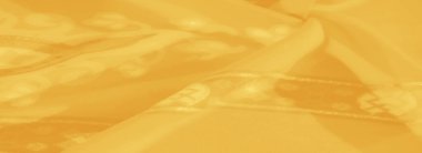 Karmaşık çiçek ve geometrik detaylarla sarı kumaşın bulanık görüntüsü, zarif tekstil temaları için ışıldayan dokuyu ve canlı renkleri vurguluyor..