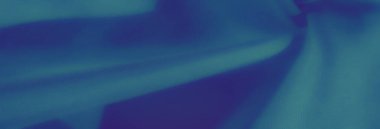 Görüntü. Yumuşak ve akışkan kıvrımlı bir kumaş, koyu mavi tonlara sahip. Doku pürüzsüz gölgelerle vurgulanır ve görsel olarak rahatlatıcı bir kompozisyon yaratır..