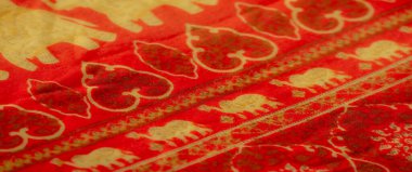 Bulanık kırmızı kumaş altın filler ve karmaşık dekoratif tasarımlar sergiliyor. Kültürel zenginlik ve zarafet yayıyor..