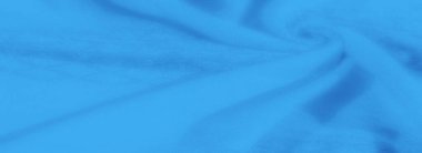 Görüntü. Nazik kıvrımları ve yumuşak dokuları olan mavi kumaşlardan oluşan bir yakın plan, sakin ve soyut bir desen yakalıyor. Işık ve gölge kumaşları güçlendiriyor.,