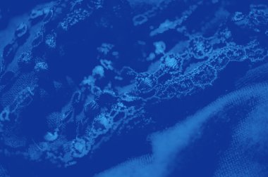 Hassas, dantel gibi dokuları olan, karmaşık desenler ve lüks bir his için hafif ışık etkileşimiyle vurgulanmış koyu mavi kumaşın bulanık sunumu