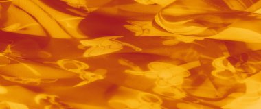 Parlayan turuncu kumaşın bulanık çizgili ve çiçekli tasarımları, yumuşak, dalgalı katmanları ışıl ışıl ışık ve sıcak, sanatsal cazibe için davetkar tonlarla birleştiriyor..